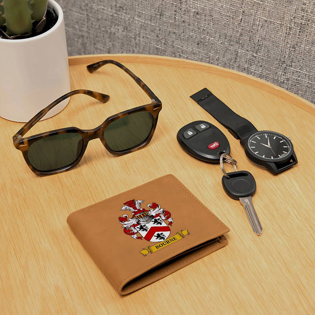 Personalized brown wallet with coat of arms design, sunglasses, car keys, and watch on a wooden table.