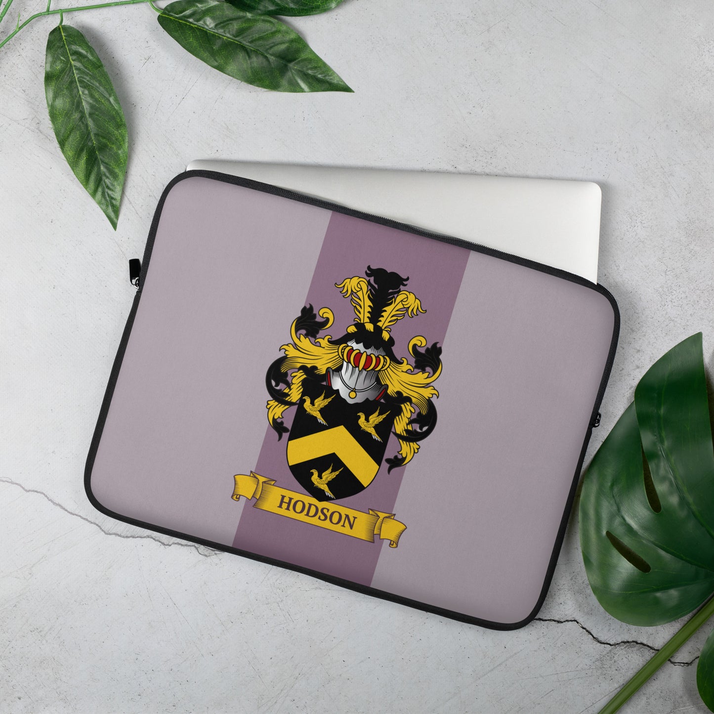Mauve laptop sleeve with a family crest design on a light gray background