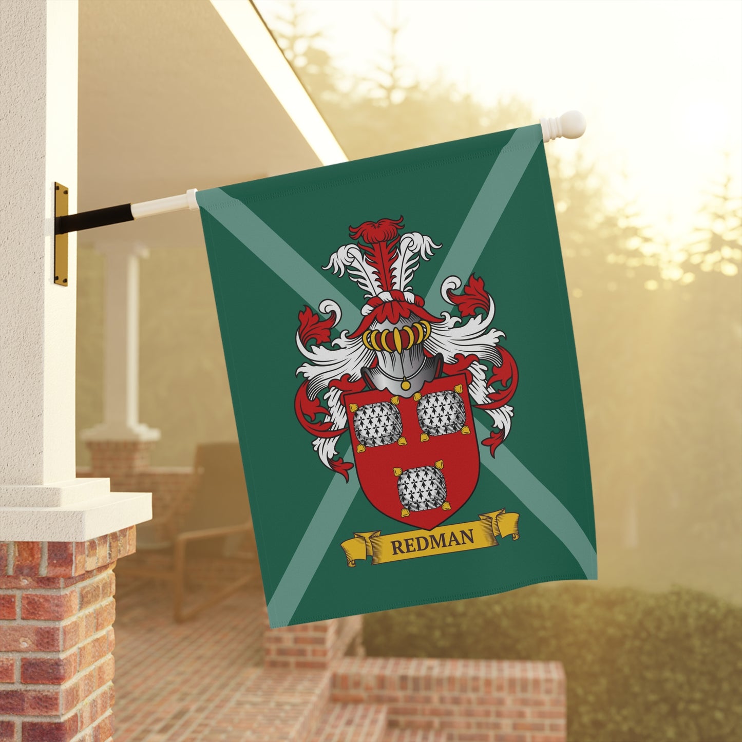 Green garden Flag with a coat of arms and 'Redman' last name on it,  hanging on a flagpole outdoors.
