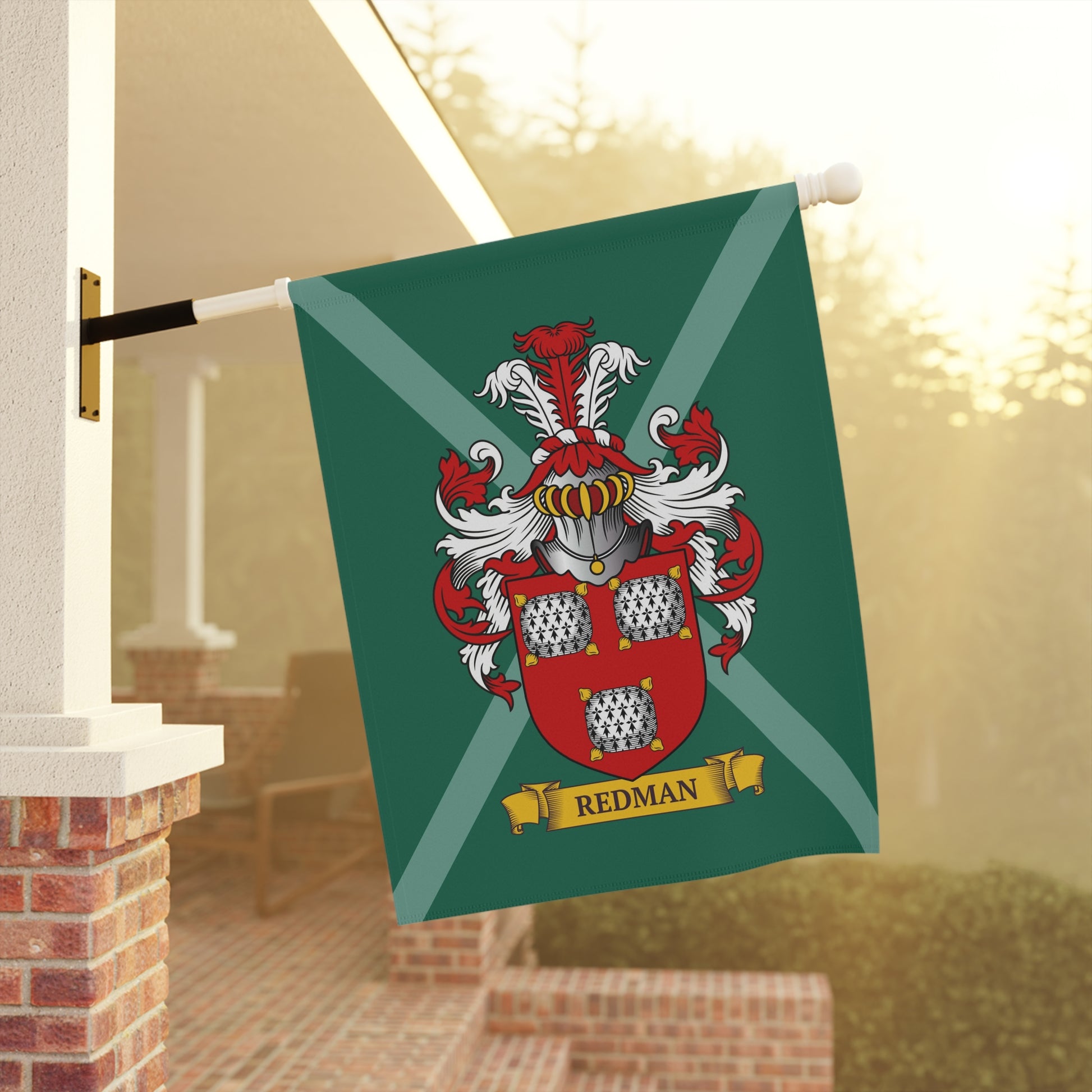 Green garden Flag with a coat of arms and 'Redman' last name on it,  hanging on a flagpole outdoors.