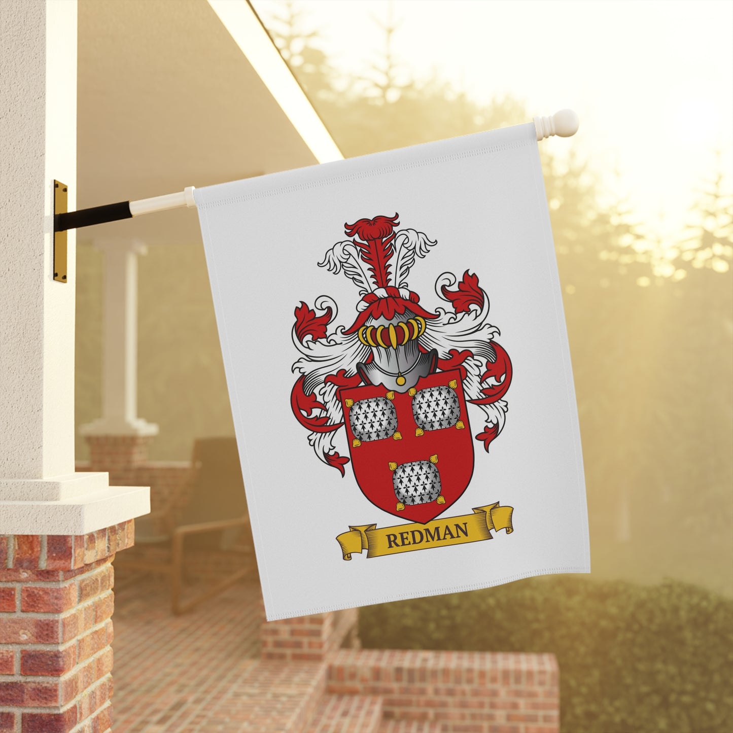 Family crest white garden flag with 'Redman' last name on a pole against a blurred outdoor background