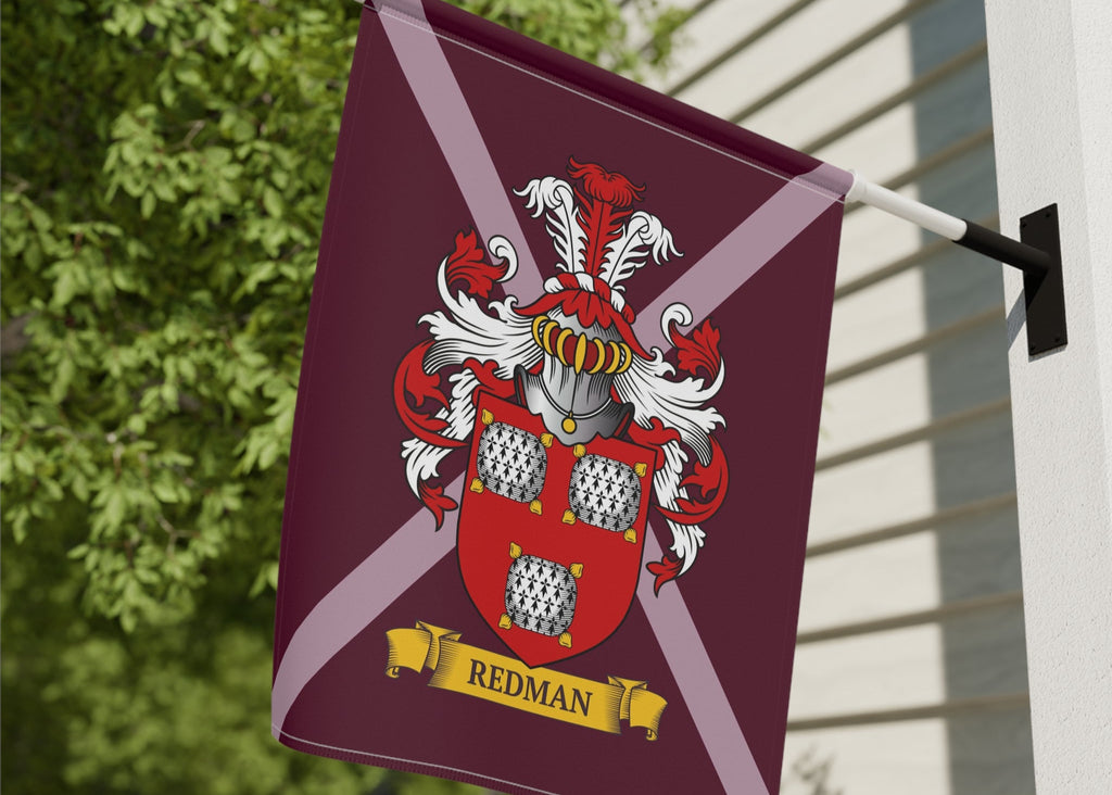 Personalized burgundy red family crest garden flag on a pole against a building and a tree background