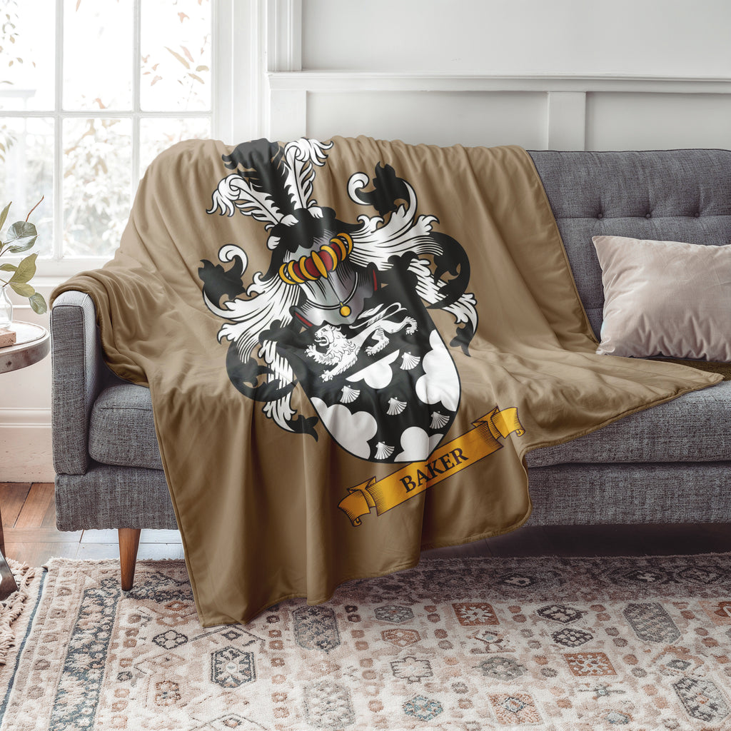 Personalized beige Blanket with a family crest design featuring the last name 'Baker' draped over a gray sofa in a living room.