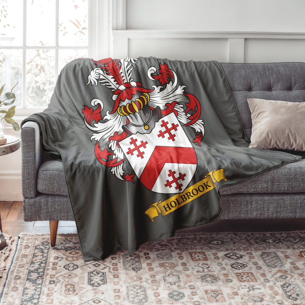 Personalized Gray blanket with a family crest design featuring the last name 'Holbrook' draped over a gray sofa in a living room.
