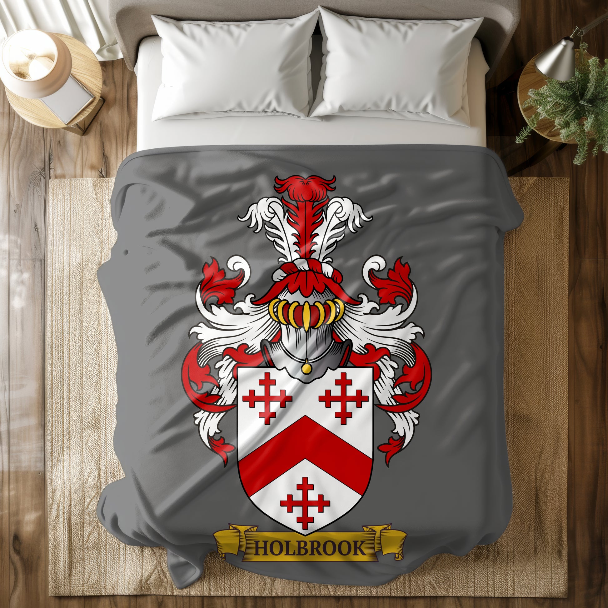 Gray velveteen blanket with a red and white family crest and 'Holbrook' last name on a bed.
