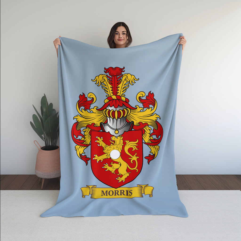 Person holding a velveteen pastel blue blanket with a family crest print 