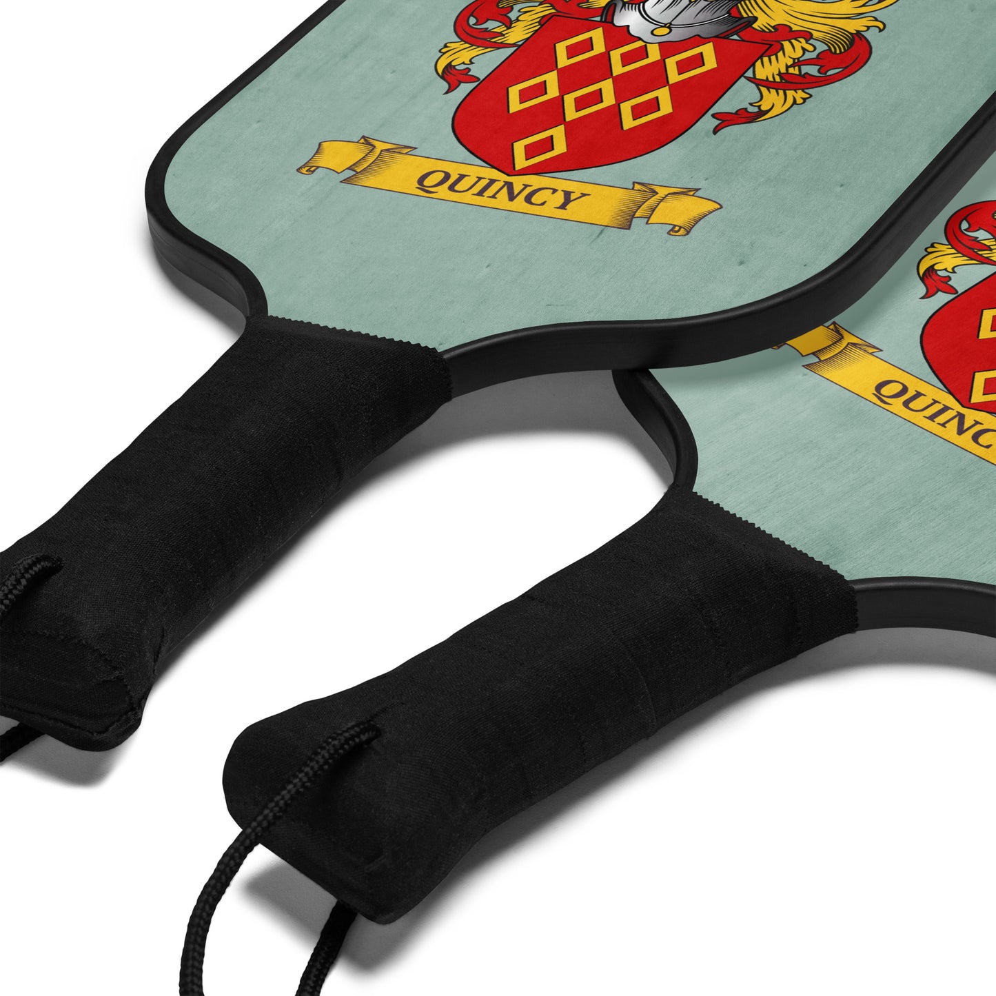 Two pickleball paddles with a visible crest and the name 'Quincy' on a light green background.