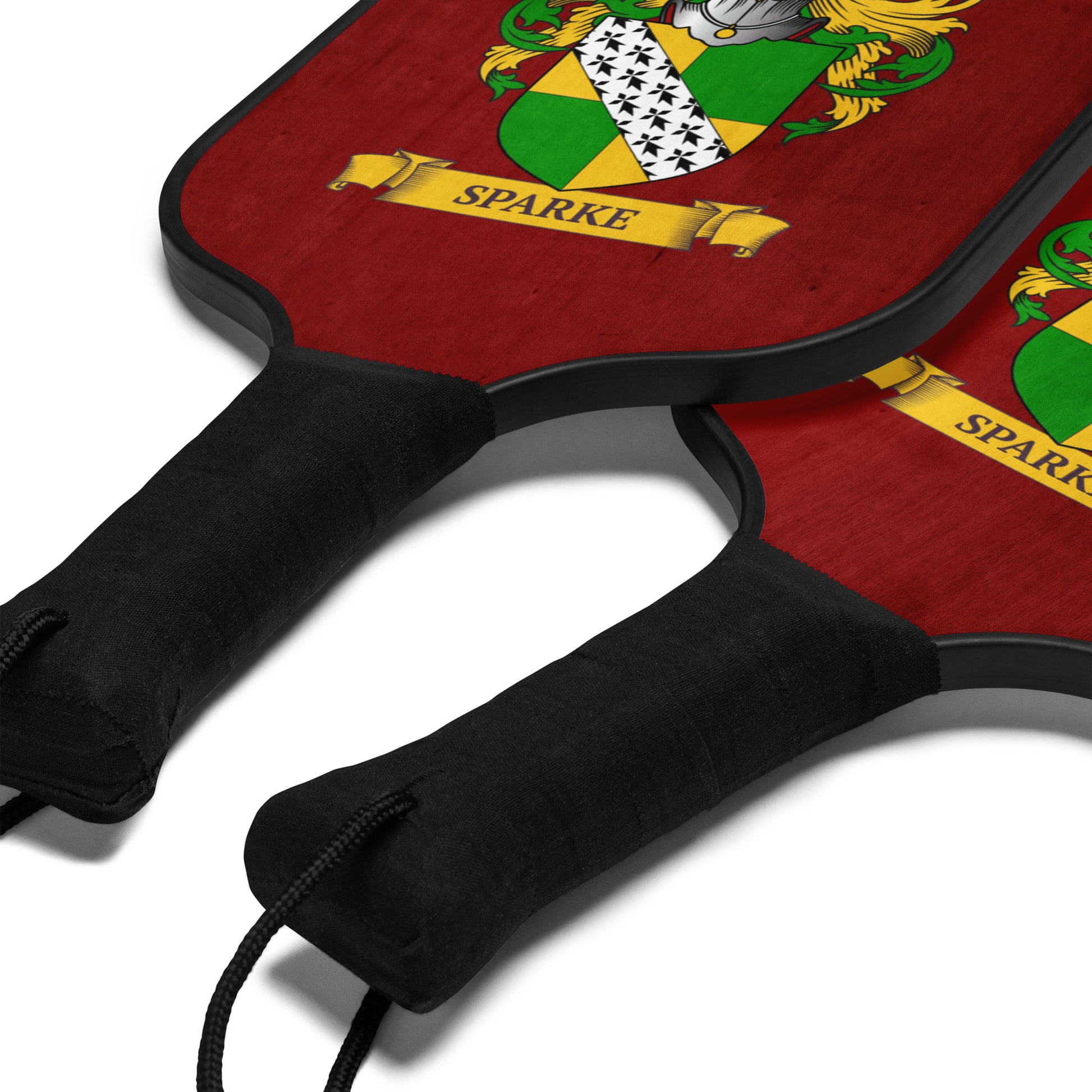 Two pickleball paddles with Sparke family crest design on a red background