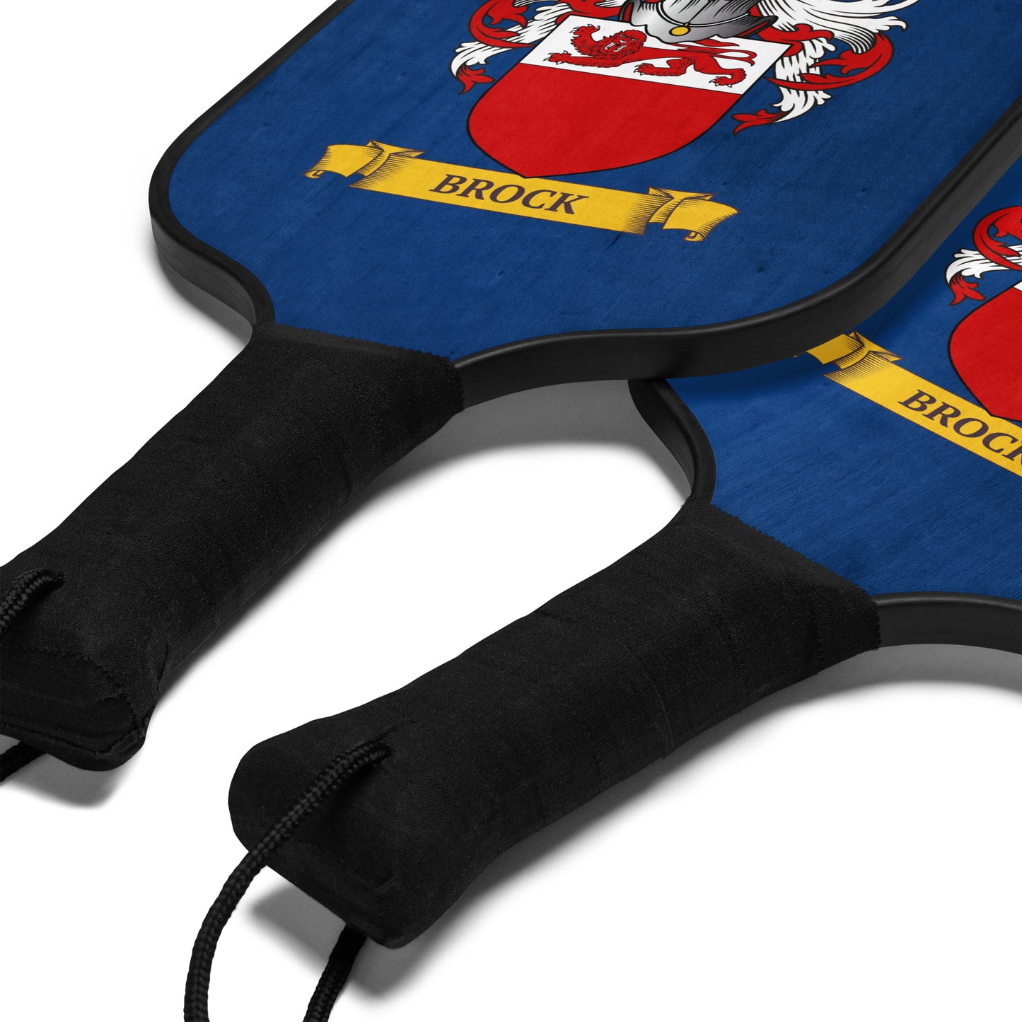 Two navy blue pickleball paddles with personalized family crest design on a blue background